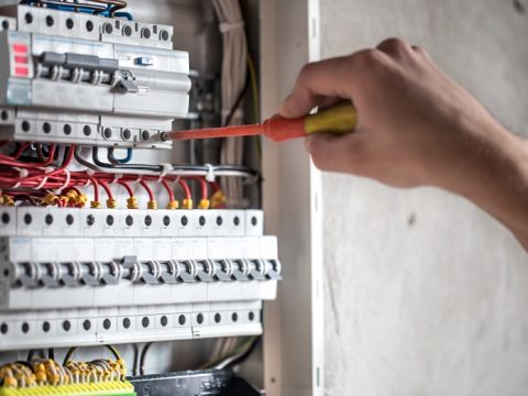 man-electrical-technician-working-switchboard-with-fuses-installation-connection-electrical-equipment-close-up